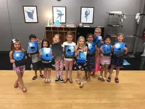 a group of children wearing matching t-shirts and standing in a room