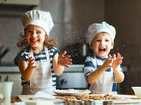 a couple of kids wearing white hats and aprons