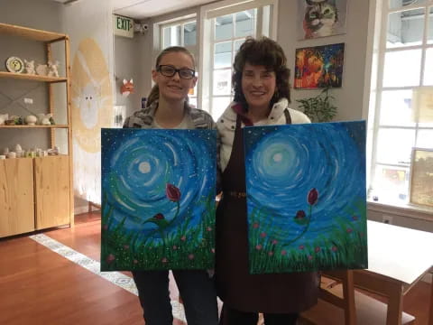 two women holding paintings