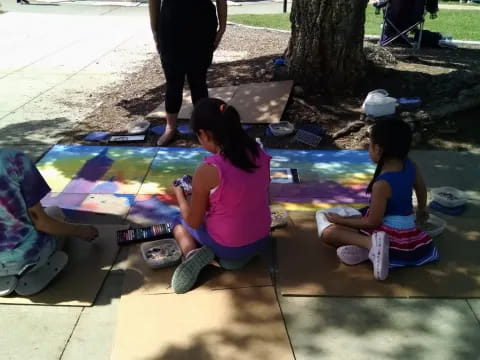 a group of children sitting on a mat outside