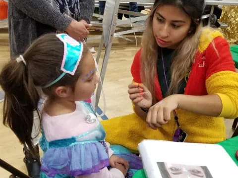 a person painting a girl's face