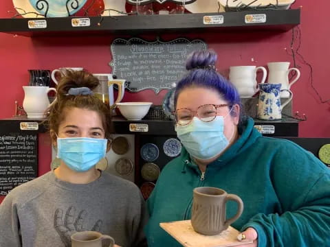 a couple of people wearing masks and holding coffee cups