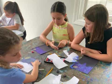 a group of children sitting at a table painting