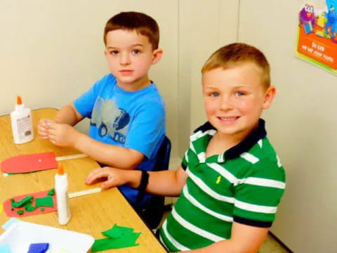 a couple of boys sitting at a table with a toy