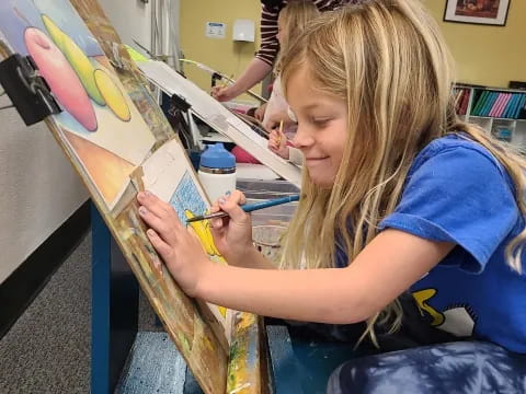 a girl painting on a canvas