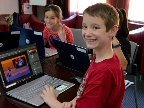 a young boy smiling while using a laptop