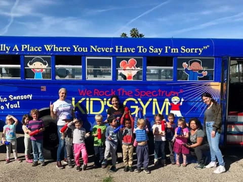 a group of people posing for a photo in front of a blue bus