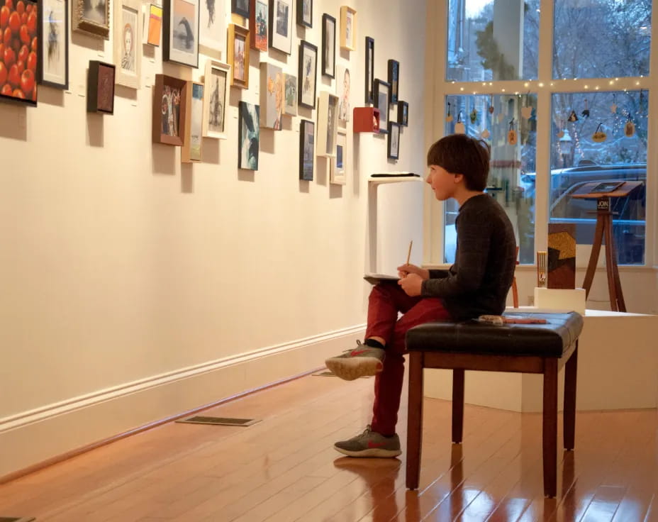 a person sitting on a chair in a room with pictures on the wall