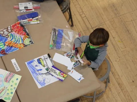 a child sitting at a table with a book and drawings on it