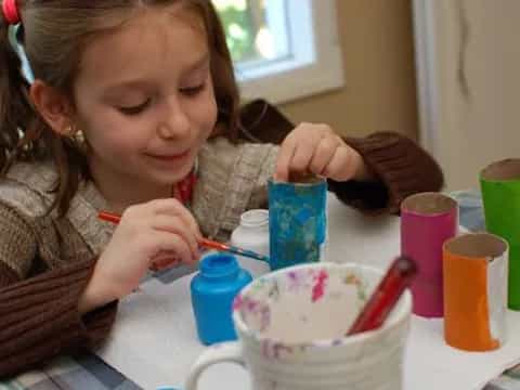 a girl painting a cup