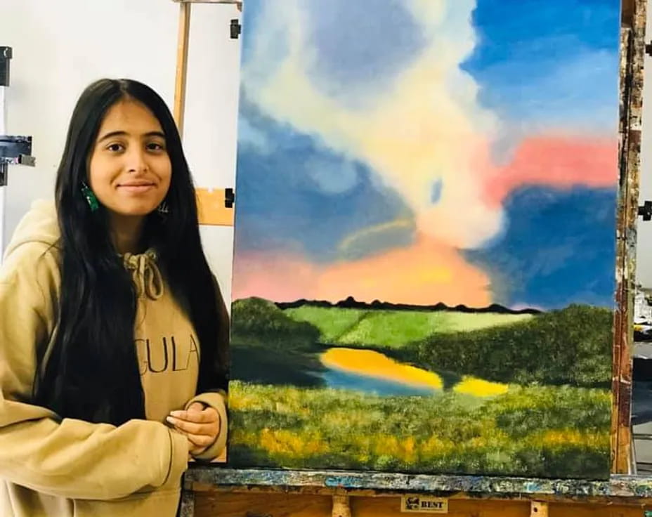 a woman standing next to a painting