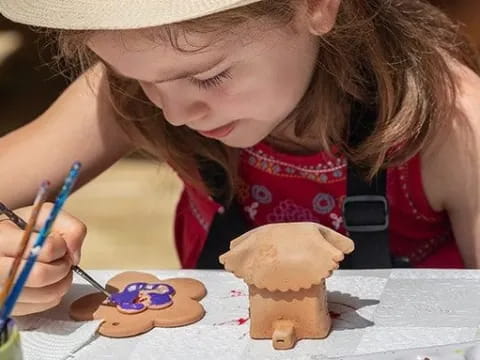 a girl painting a gingerbread house