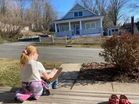 a girl sitting on a bench in front of a house