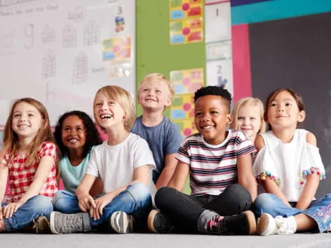 a group of children sitting on the floor smiling for the camera