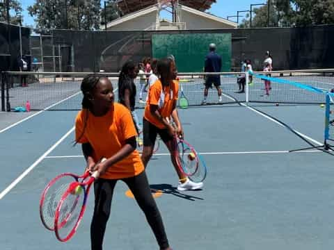 a group of girls holding tennis rackets on a court