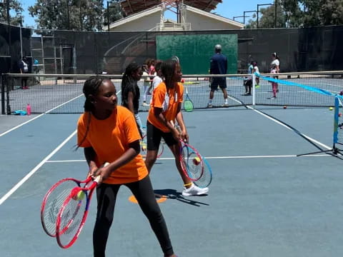 a group of girls holding tennis rackets on a court