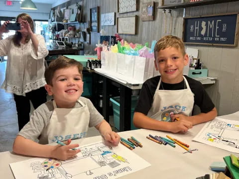 a couple of boys sitting at a table with a drawing
