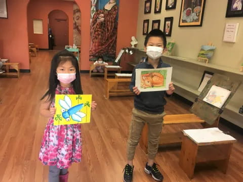 a boy and girl holding paintings