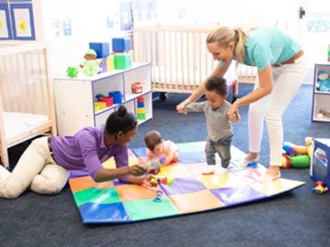 a person and kids playing on a rug in a room