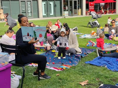 a person reading a book to a group of children