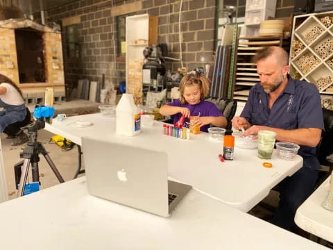 a person and a child at a table with a laptop