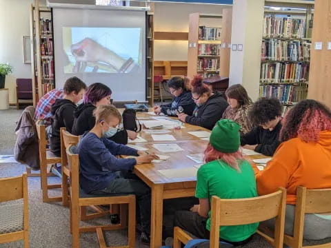 a group of people sitting around a table watching a presentation