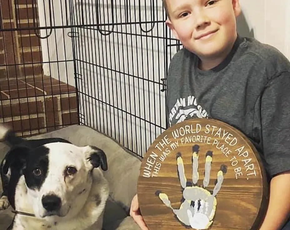 a boy holding a plaque with a dog in the background