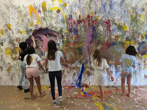 a group of children walking in front of a painting