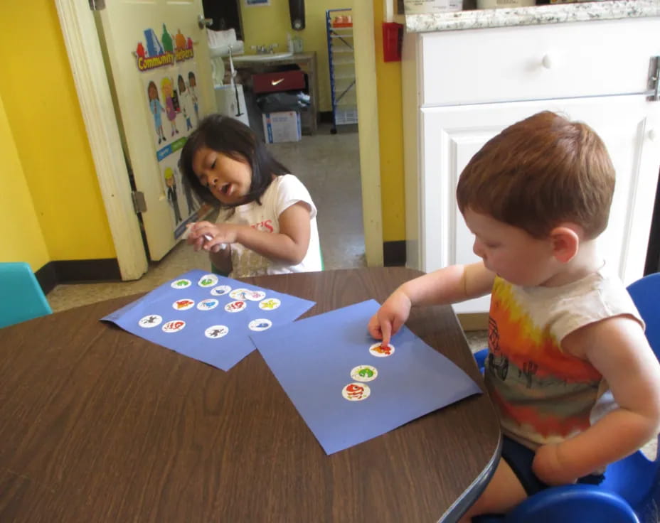 a couple of kids playing with a blue and white puzzle on a table