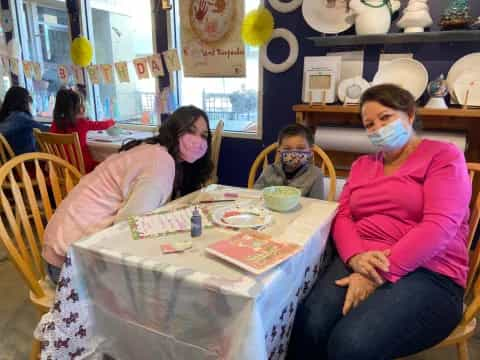 a group of people sitting at a table with masks on