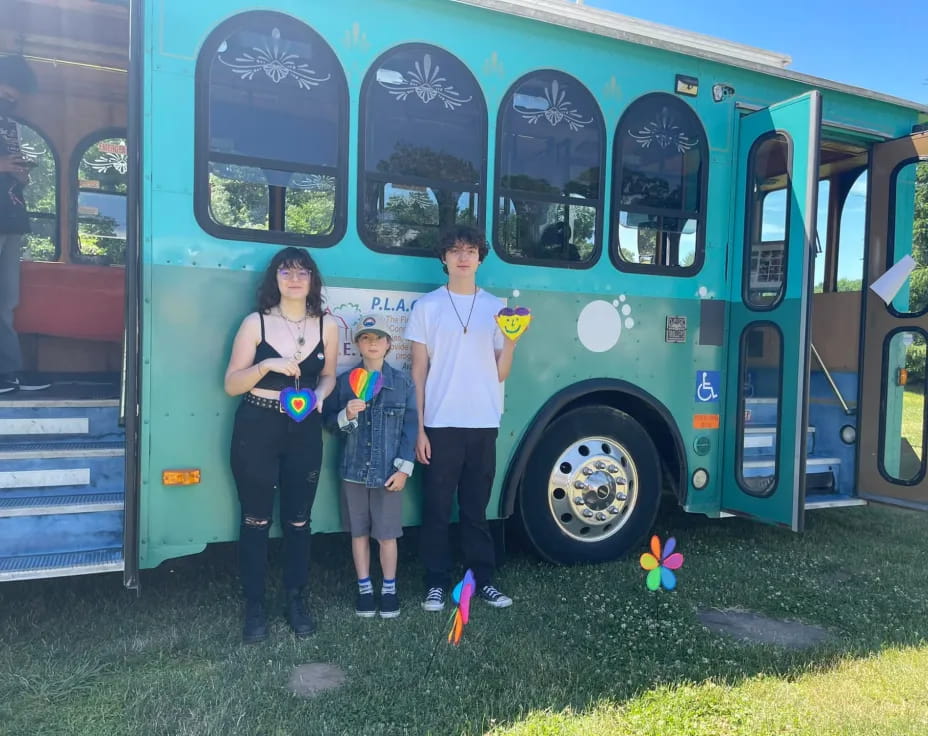 a family posing in front of a blue bus