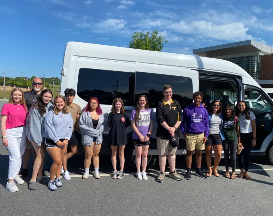 a group of people posing for a photo in front of a bus