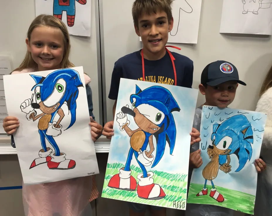 a group of children holding up drawings