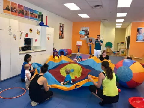 a group of children playing on a mat in a room with balloons