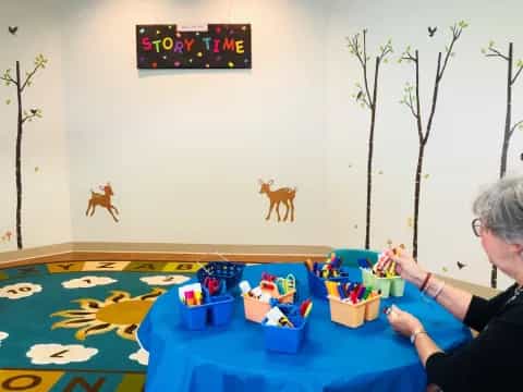 a person sitting at a table with toys and a sign on the wall