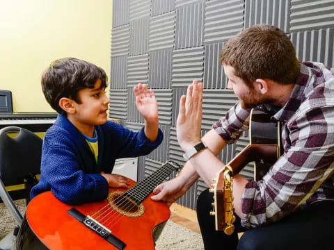a man and a boy playing a guitar