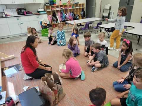 a group of children sitting on the floor in a classroom