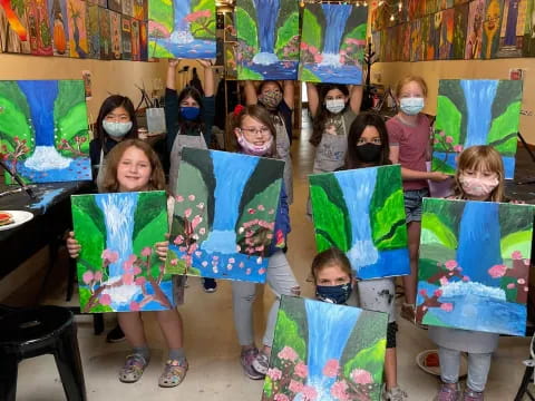 a group of children holding up paintings