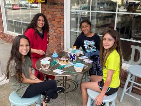 a group of women sitting around a table outside