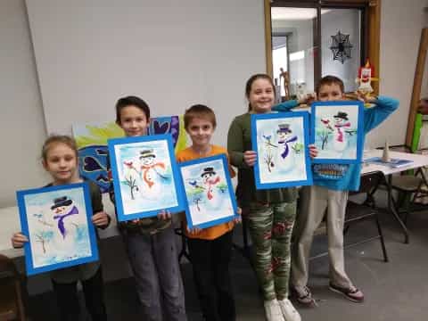 a group of children holding up framed pictures