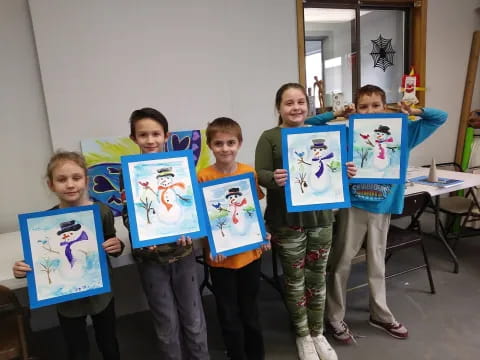 a group of children holding up framed pictures