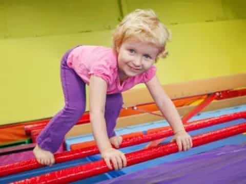 a child on a red and yellow trampoline