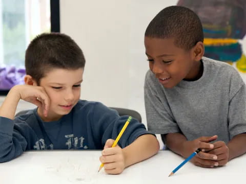 a couple of boys sitting at a table with toothbrushes