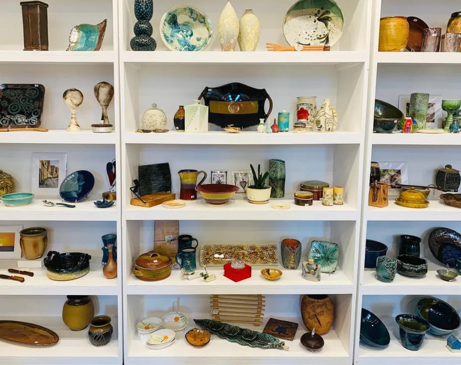 a shelf with many vases and bowls on it