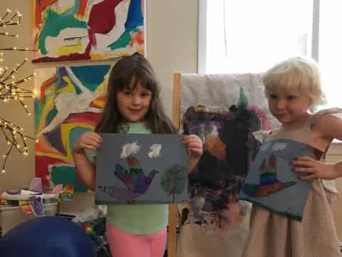 a couple of children holding paintings
