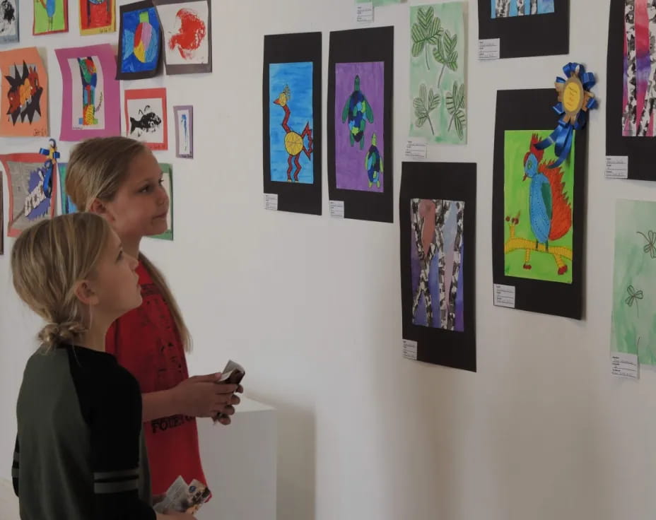 a couple of women looking at a wall of art