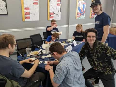 a group of people sitting around a table with computers