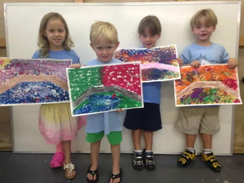 a group of children holding up paintings