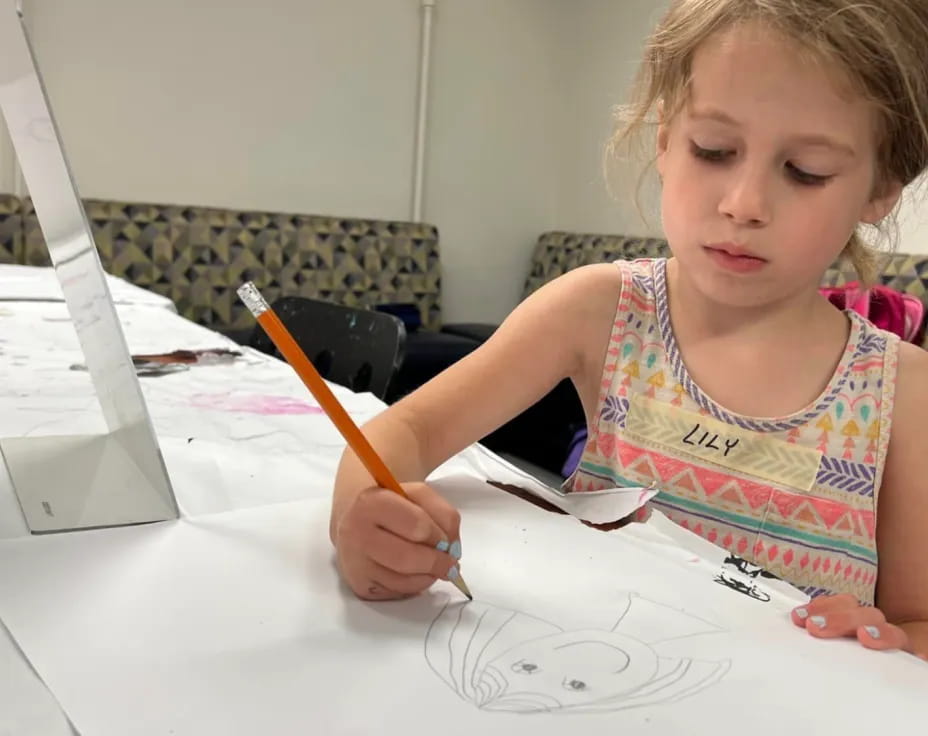 a young girl drawing on a white paper