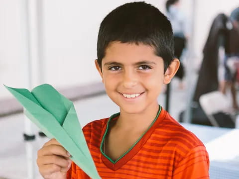 a boy holding a green paper airplane